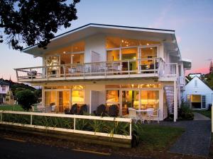 Cette grande maison blanche dispose d'un balcon et d'une table. dans l'établissement Hananui Lodge and Apartments, à Russell