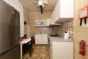 a kitchen with white cabinets and a table and a ceiling at Lovely House Private Rooms by Vallettastay in Valletta