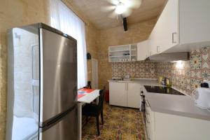a kitchen with a stainless steel refrigerator and a table at Lovely House Private Rooms by Vallettastay in Valletta +11 photos