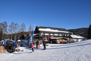 un gruppo di persone sugli sci nella neve vicino a un rifugio per sciatori di Alpengasthof Eichtbauer a Spital am Semmering