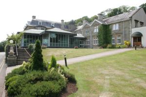 ein großes Haus mit Rasen davor in der Unterkunft The Manor House At Celtic Manor in Newport