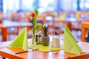 a table with green napkins and a flower in a vase at Hotel Stoiser Graz in Graz
