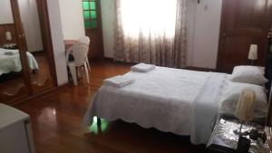 a bedroom with a white bed and a wooden floor at Hostal Camiluz in Nazca