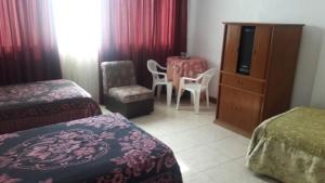 a hotel room with two beds and a table and chairs at Hostal Camiluz in Nazca