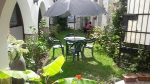 a patio with a table and chairs and an umbrella at Hostal Camiluz in Nazca