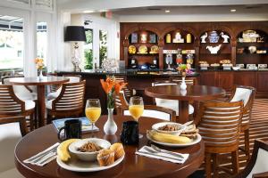 a restaurant with tables and chairs with food and drinks at Inn at Pelican Bay in Naples