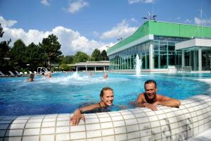 two people swimming in a swimming pool with a building at Parkhotel Bad Bevensen ,ThermePlus in Bad Bevensen