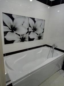 a white tub in a bathroom with a picture of flowers at Apartment on Zhaloytskaga 35 in Pinsk