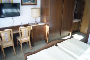 a bedroom with a bed and a desk and a tv at Gästehaus Charlotte in Bayrischzell +12 photos