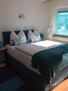un letto con cuscini blu e bianchi e una finestra di Gästehaus Anna a Grossarl