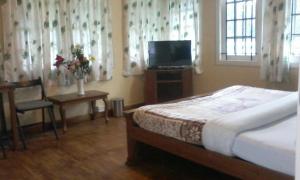 a bedroom with a bed and a tv and a table at Rainforest Munnar in Munnar