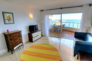 uma sala de estar com um sofá, uma televisão e uma varanda em C16013 Club de Mar em Sant Feliu de Guíxols