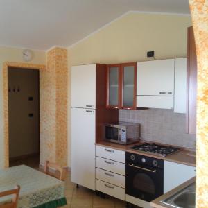 una cucina con mobili bianchi e un forno a piano cottura di L' Alba di Alice a Silvi Marina
