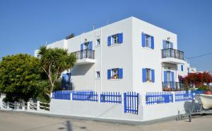 a white building with blue windows and a blue fence at Veletas Apartments in Adamantas
