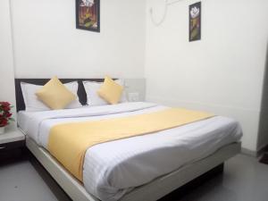 Hotel Gopi Palace في أحمد آباد: غرفة نوم بسرير ذو شراشف ومخدات صفراء وبيضاء