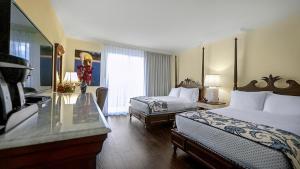 a hotel room with two beds and a glass table at Inn at Pelican Bay in Naples