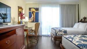 a hotel room with a bedroom with a bed and a desk at Inn at Pelican Bay in Naples