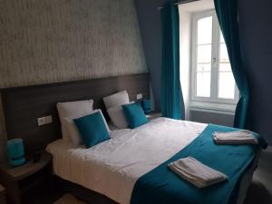 a bedroom with a bed with blue pillows and a window at H&ocirc;tel Le Saint Patrice in Bayeux