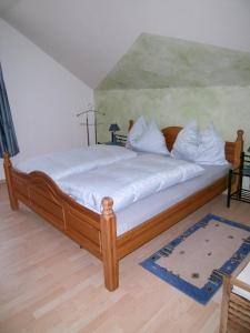 Schlafzimmer mit einem Holzbett mit weißer Bettwäsche in der Unterkunft Haus Anika Ferienwohnung in Mallnitz