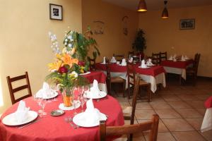 un comedor con mesas rojas y sillas con flores. en Au Bon Accueil, en Arvieu