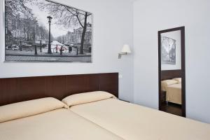 1 dormitorio con cama y espejo en Hostal T4, en Paracuellos de Jarama