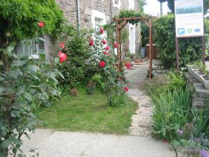 un giardino con rose rosse e un edificio di Appartements Couleurs de Mer CANCALE a Cancale