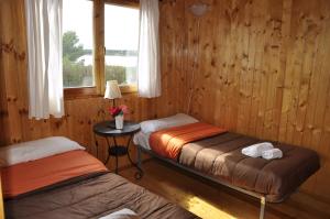 2 camas en una habitación con paredes de madera y ventana en Camping La Estanca, en Alcañiz