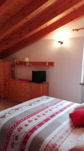 sypialnia z łóżkiem z telewizorem na ścianie w obiekcie Sweet Home Casa Vacanze "La Mansarda" w mieście Rovetta