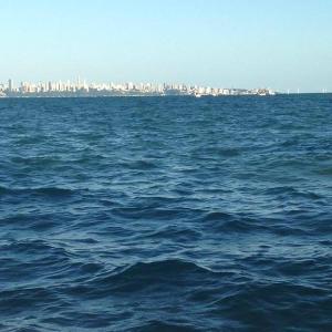 a large body of water with a city in the background at Apart-Hotel Beira Mar em Mar Grande - Vera Cruz - Ilha de Itaparica in Aratuba Beach