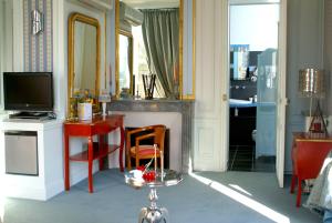 a living room with a television and a desk with a mirror at La Gourmandine in Châtellerault