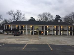 a large building with a car parked in a parking lot at The Cullars Inn in Lincolnton