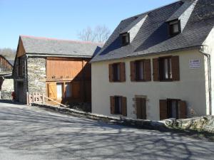 ein weißes Gebäude mit braunen Fensterläden auf einer Straße in der Unterkunft appartement vacances à la montagne RDC in Génos