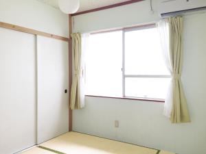 an empty room with a window with curtains at Matsukaze The Guest House Ishigaki in Ishigaki Island