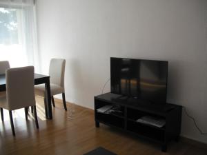 ein Wohnzimmer mit einem TV, einem Tisch und Stühlen in der Unterkunft Residence Le Vendome in Dijon