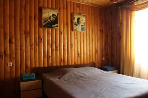 a bedroom with wooden walls with a bed and pictures on the wall at Hotel-complex Mizh Triokh Ozer in Svityazʼ