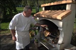 a man standing next to an outdoor oven at Chambres d'Hôtes Le Moulin du Pont in Saint-Bonnet-de-Salers
