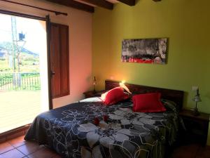 a bedroom with a bed with red pillows and a window at Posada Mediavia in Ubiarco