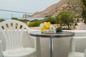 duas cadeiras brancas e uma mesa com flores em Manousos' Rooms em Galissas
