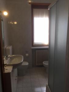 een badkamer met een wastafel, een toilet en een raam bij Casa Salice in Racconigi