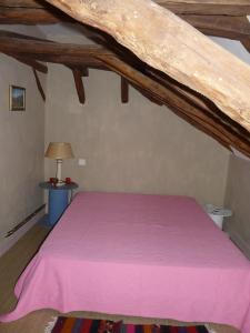 - une chambre avec un lit et une couverture rose dans l'établissement La Guelta, à Saint-Alvère