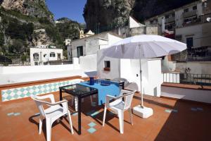 a table and chairs and an umbrella on a roof at Pompeo in Atrani