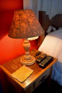 een tafel met een lamp en twee afstandsbedieningen erop bij Pousada do Getulio in Tiradentes