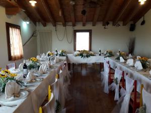 a banquet hall with long tables with white tablecloths at Agriturismo La Prateria in Gazzo