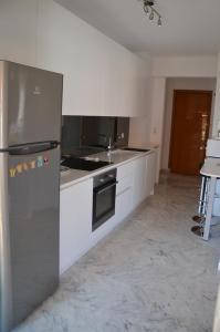 a kitchen with white cabinets and a stainless steel refrigerator at LE JAD, ROQUEBRUNE in Roquebrune-Cap-Martin