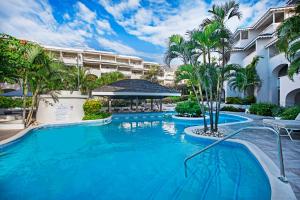 une piscine dans un complexe avec des palmiers et un bâtiment dans l'établissement Bougainvillea Barbados, à Christ Church