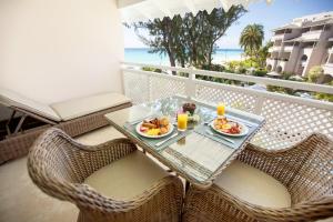 a table with two plates of food on a balcony at Bougainvillea Barbados in Christ Church