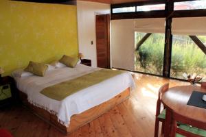1 dormitorio con cama, mesa y ventana en Cabañas Toconao, en Algarrobo