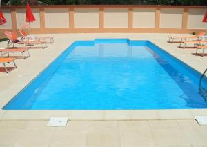 a large blue swimming pool with chairs and umbrellas at Noblesse House in Deva