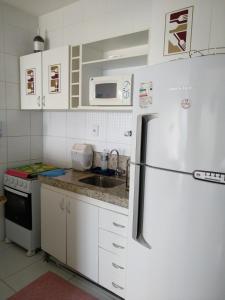 a white kitchen with a refrigerator and a sink at Jardim Armação Salvador in Salvador