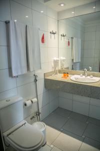 a bathroom with a toilet and a sink and a mirror at Cosmopolitan Praia Flat in Santos